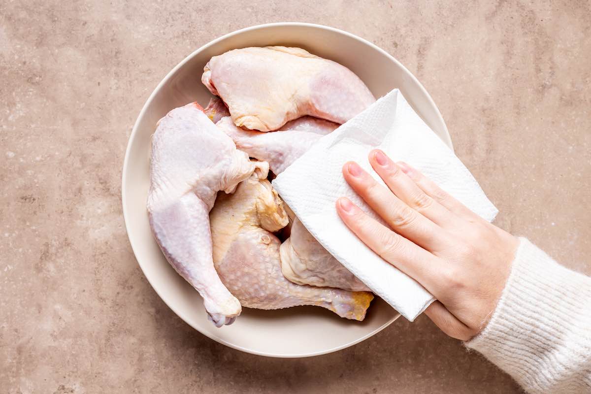 patting dry raw chicken leg quarters.