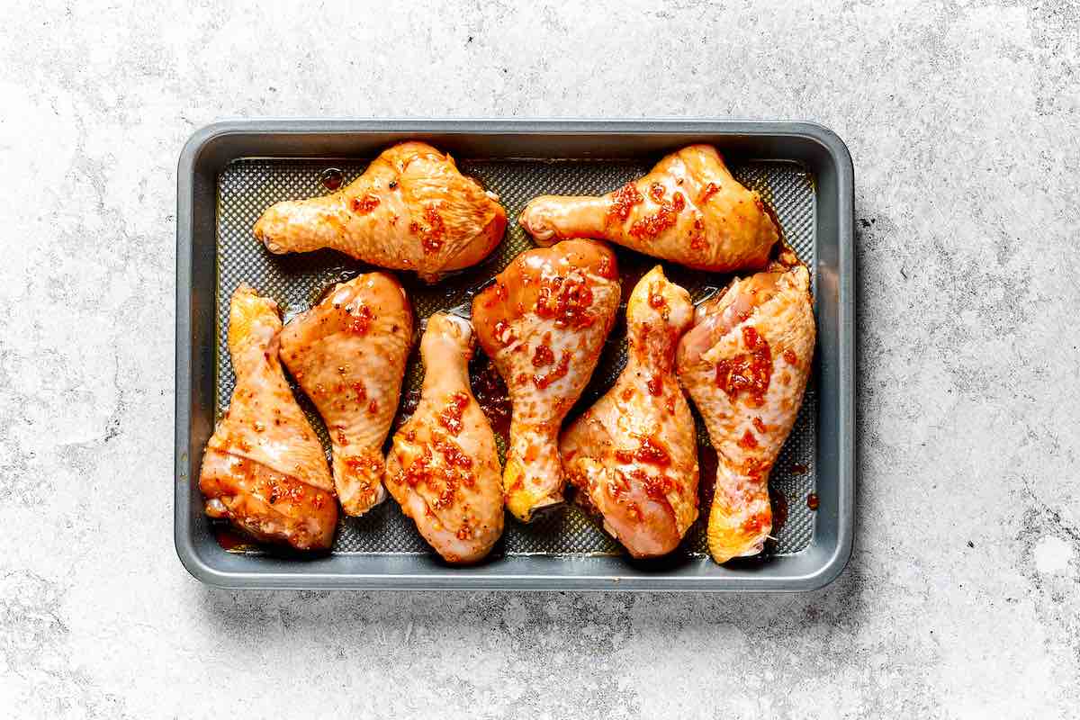 seasoned raw chicken legs on a baking sheet.