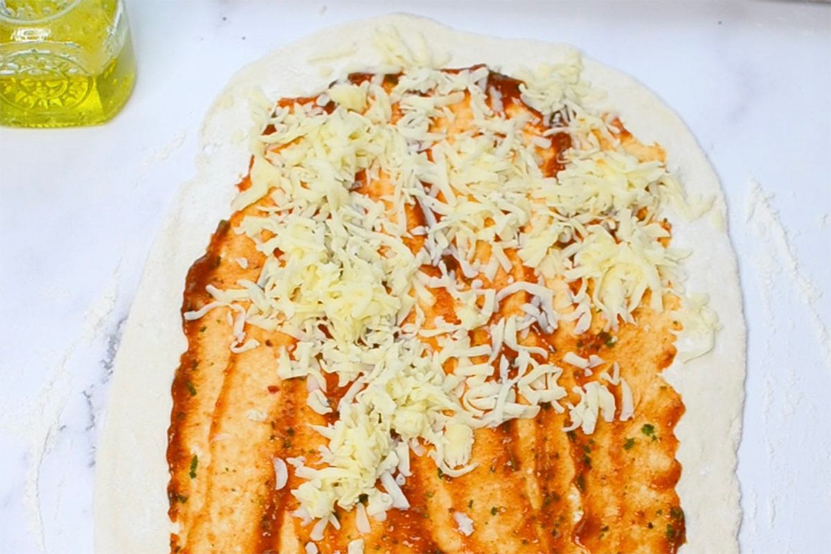 pizza dough with pizza sauce and shredded cheese on top.