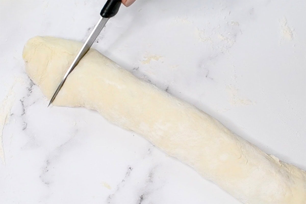 slicing rolled up pizza.