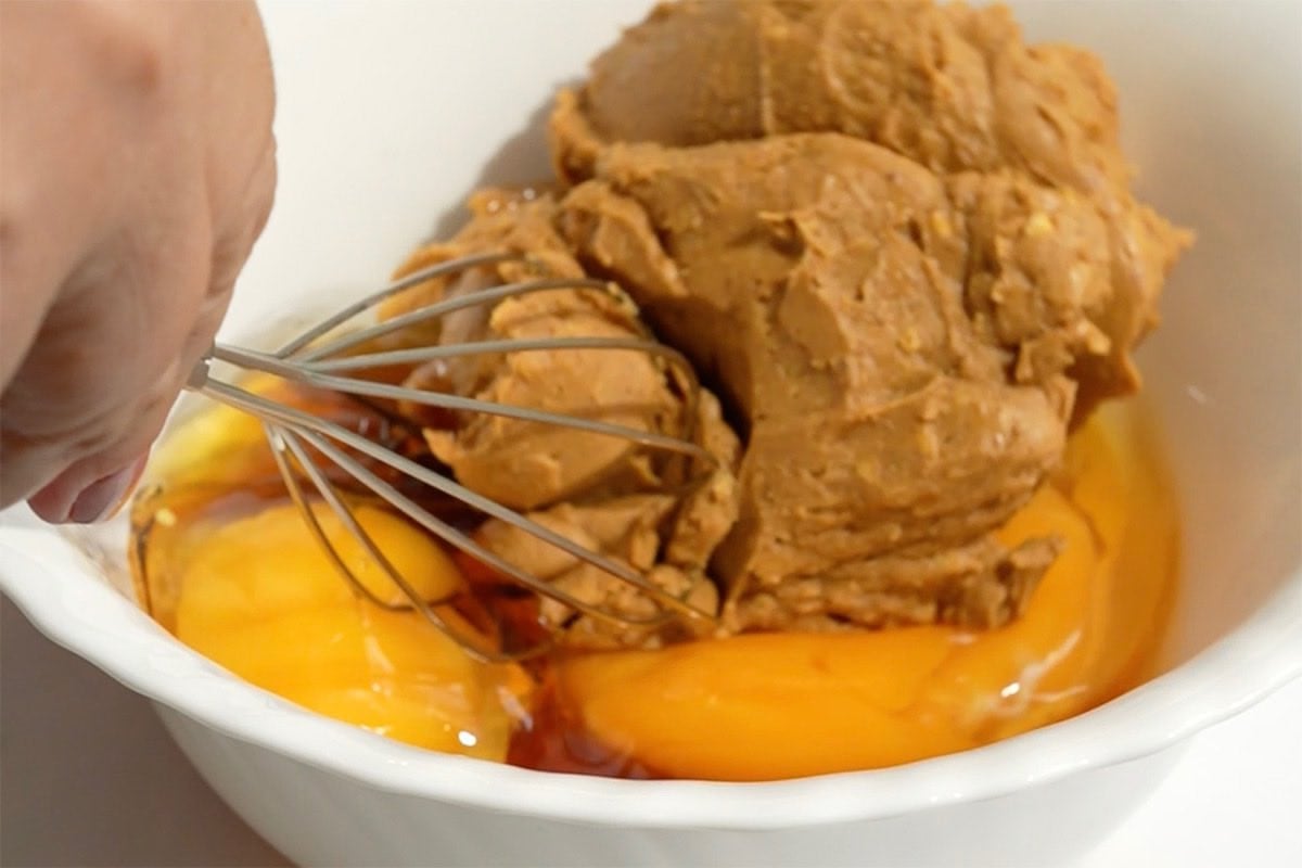 almond butter, eggs, maple syrup in a bowl.