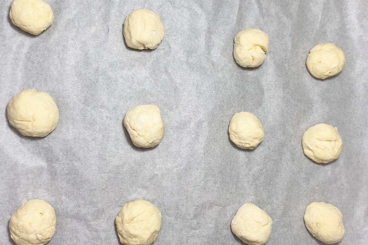 balls of dough on a lined baking sheet.