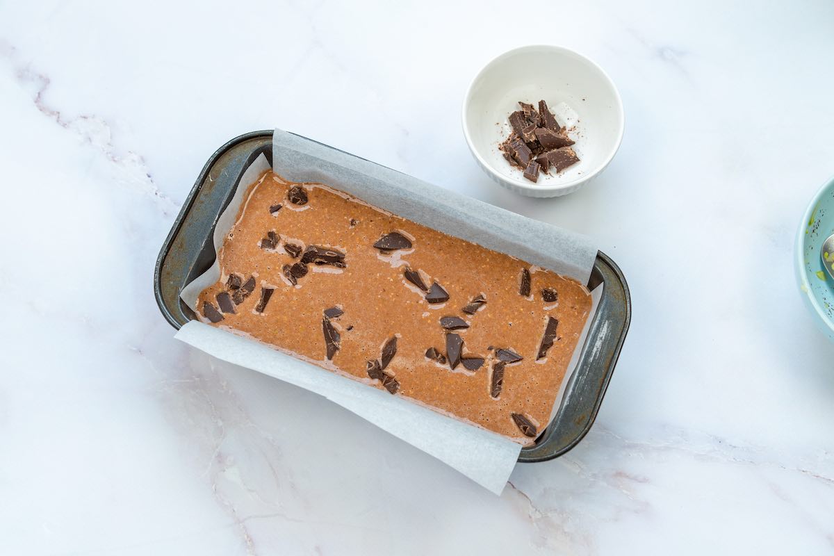 batter in loaf pan with chocolate chips on top.