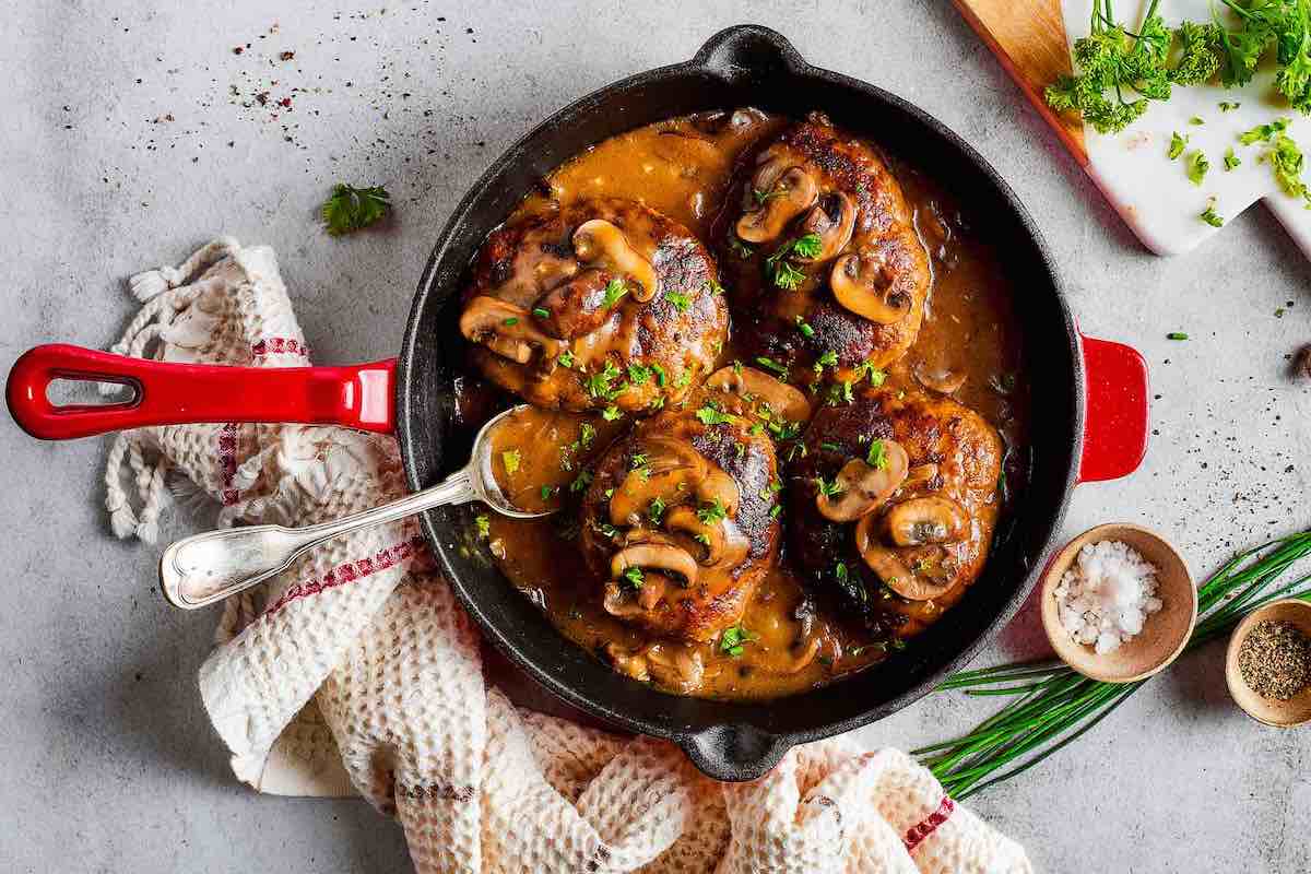 assembled Salisbury steak with mushroom gravy in a skillet.