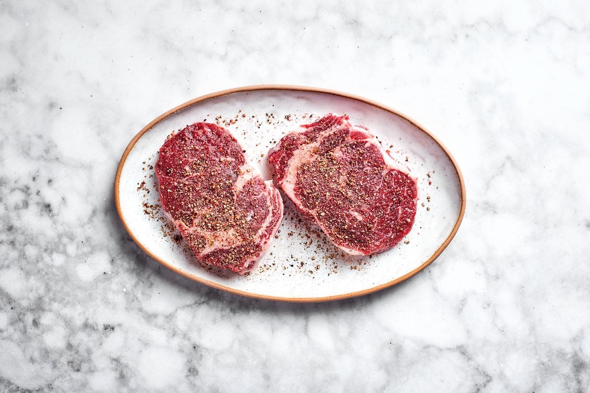 seasoned raw ribeye steaks.