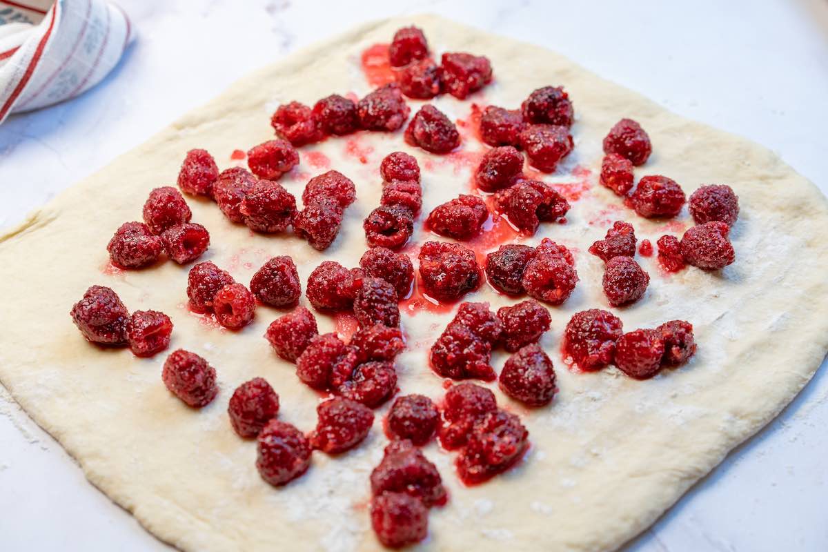 dough rolled out with raspberries and sugar.