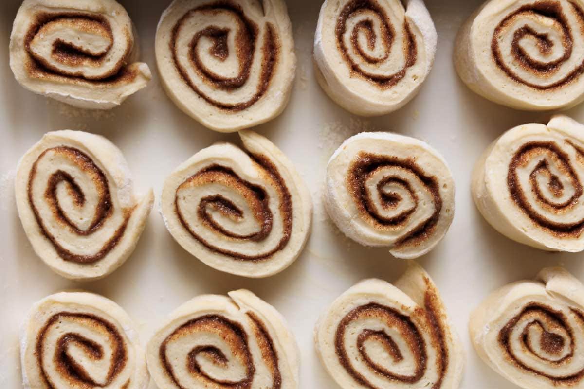 sliced unbaked vegan rolls in baking dish.