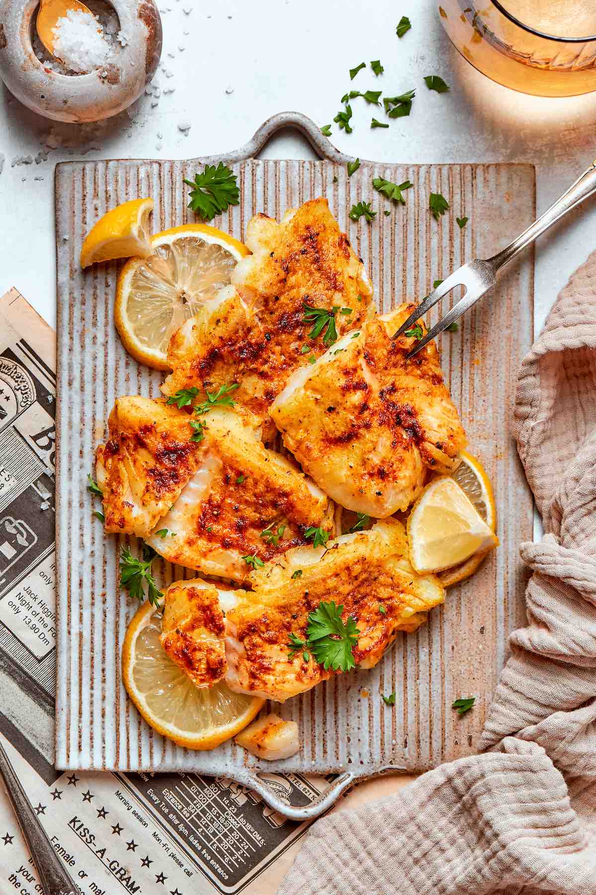 air fried halibut on a serving plate with fresh herbs on top.