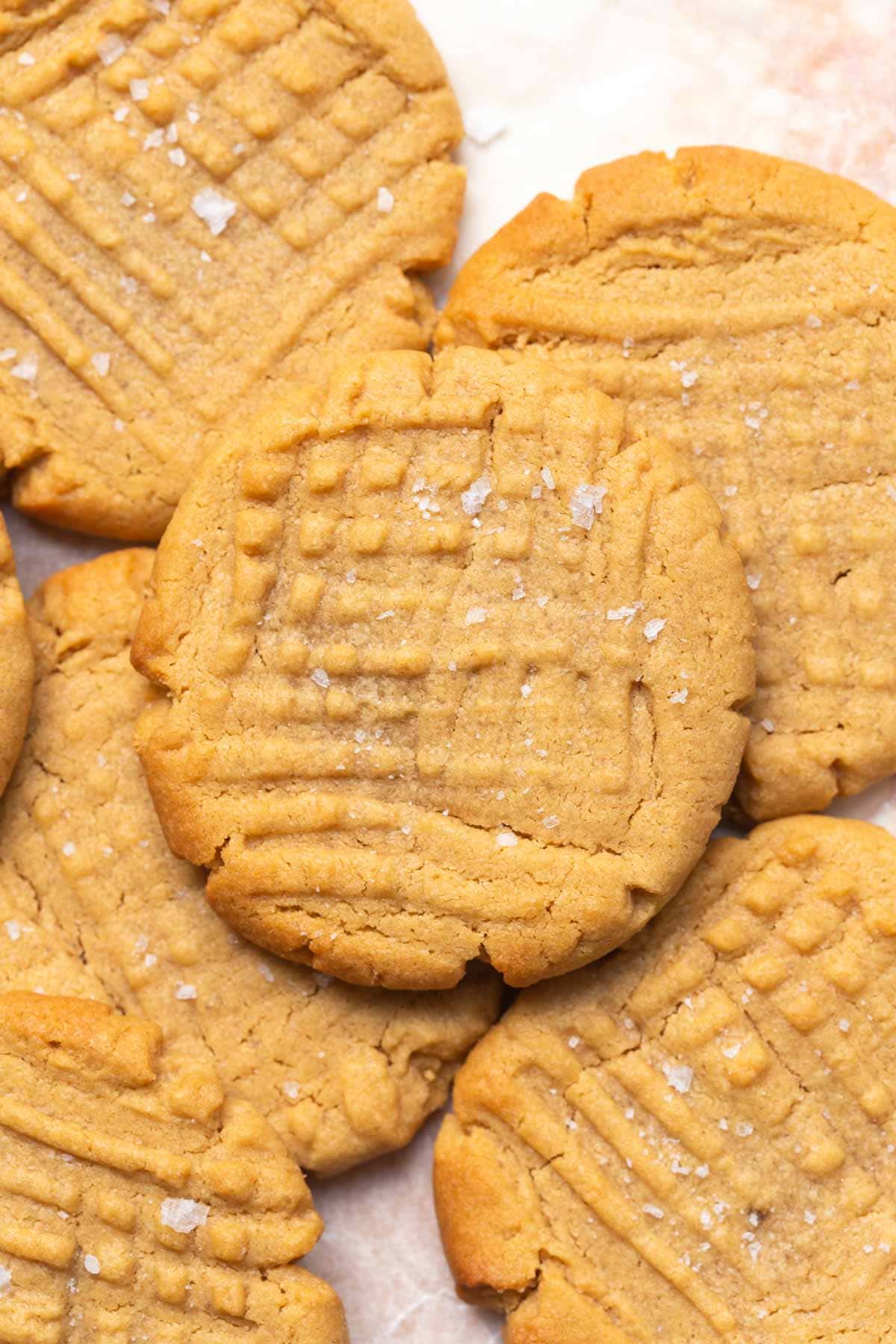 healthy peanut butter cookies on a plate with flaky salt on top.