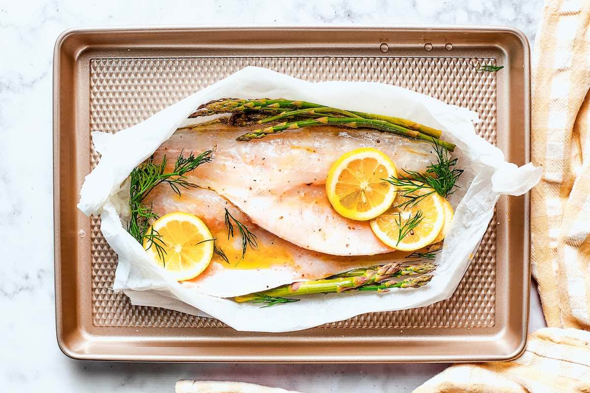 raw whiting in parchment paper with lemon and melted butter on top.