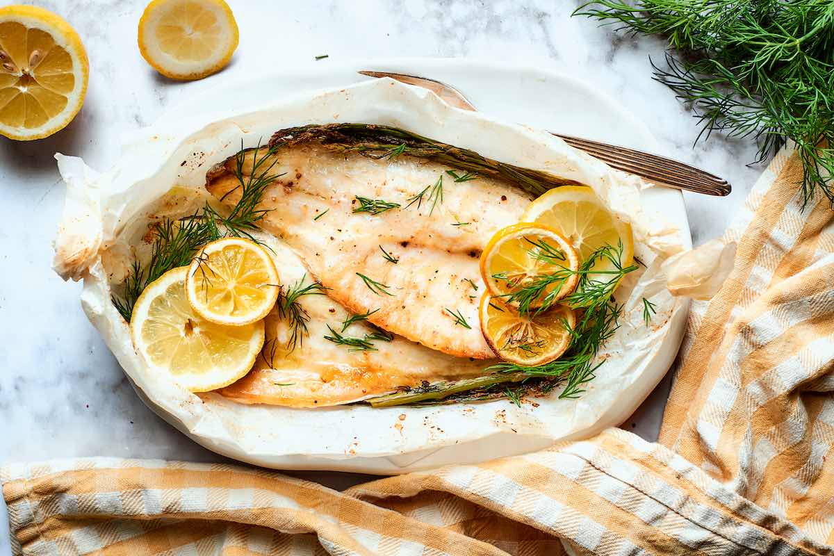 baked whiting in parchment paper with sliced lemon and dill.