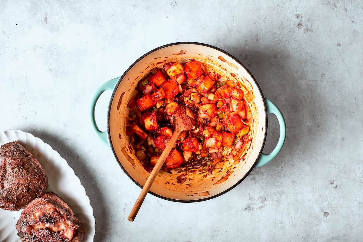 Dutch oven with onion, celery, carrots, and tomato paste.