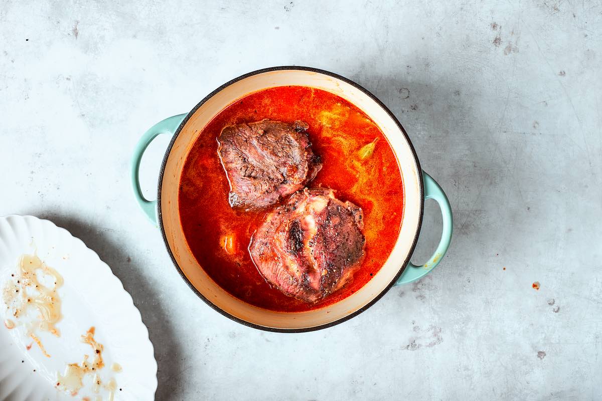 broth, vegetables, and beef cheeks in Dutch oven.