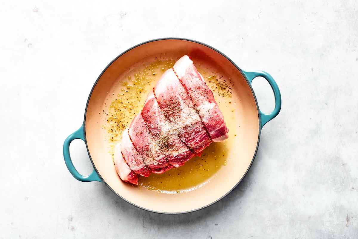 seasoned raw pork shoulder in Dutch oven.