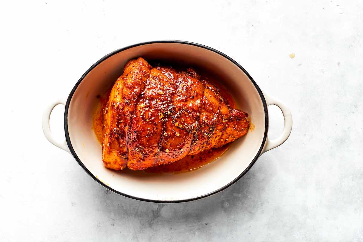 seasoned raw pork shoulder roast in Dutch oven.