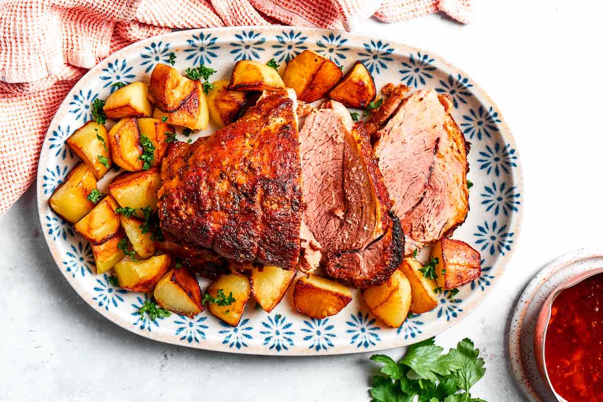 fall apart pork shoulder roast with roasted potatoes on a plate.