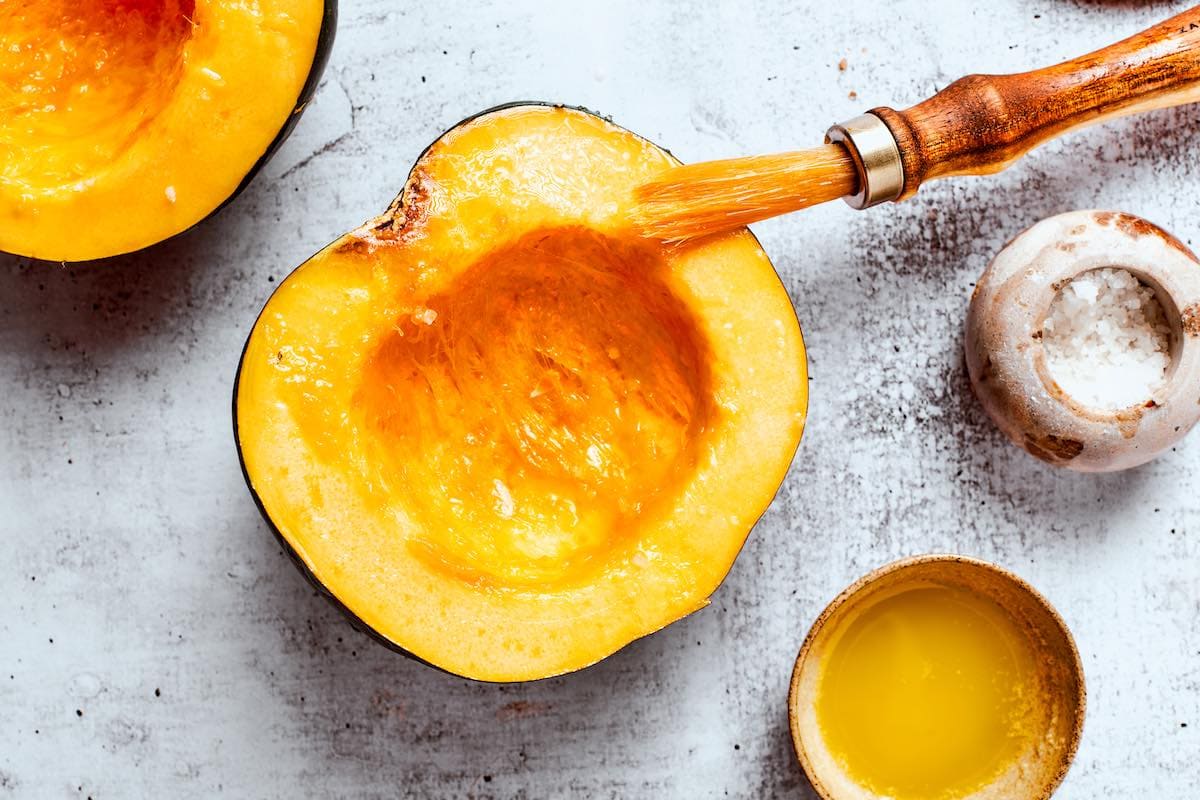 brushing uncooked acorn squash with olive oil.
