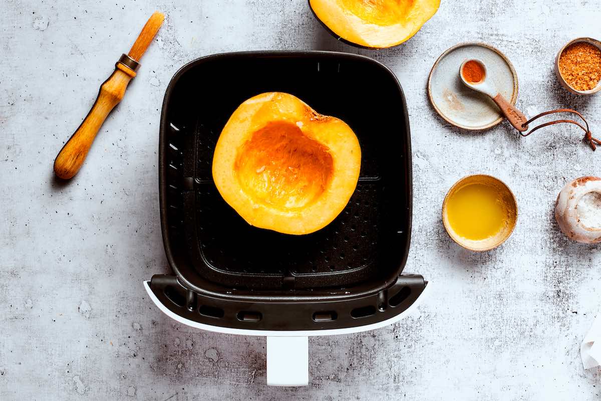 seasoned uncooked acorn squash in air fryer basket.