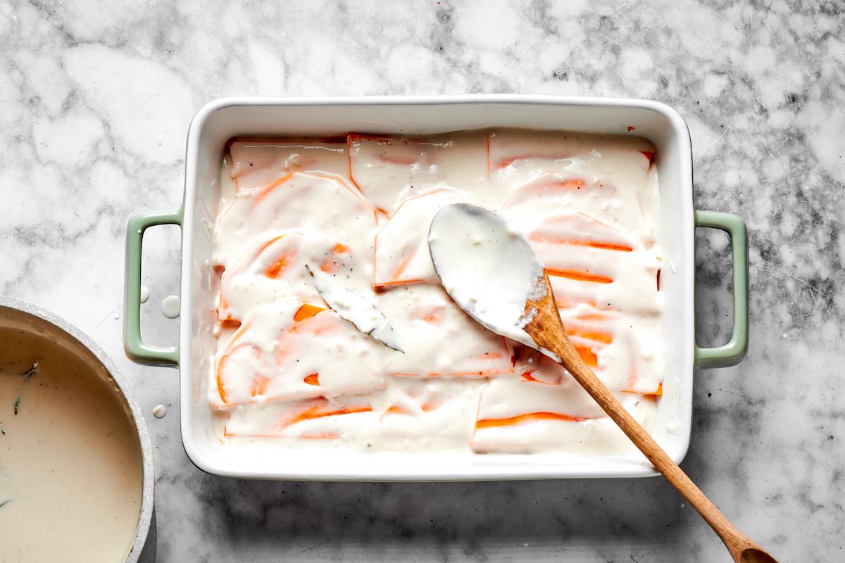 spreading cream sauce over butternut squash layer.