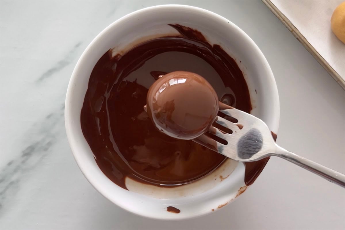 coating peanut butter balls in chocolate.
