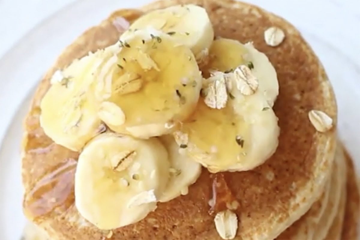 stack of pancakes with sliced banana on top.