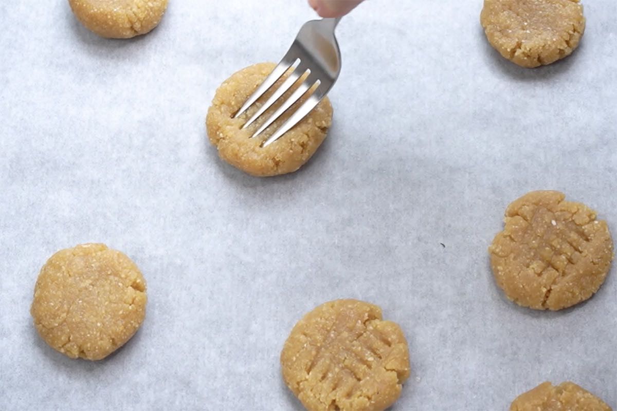 pressing down on balls of cookie dough with a fork.