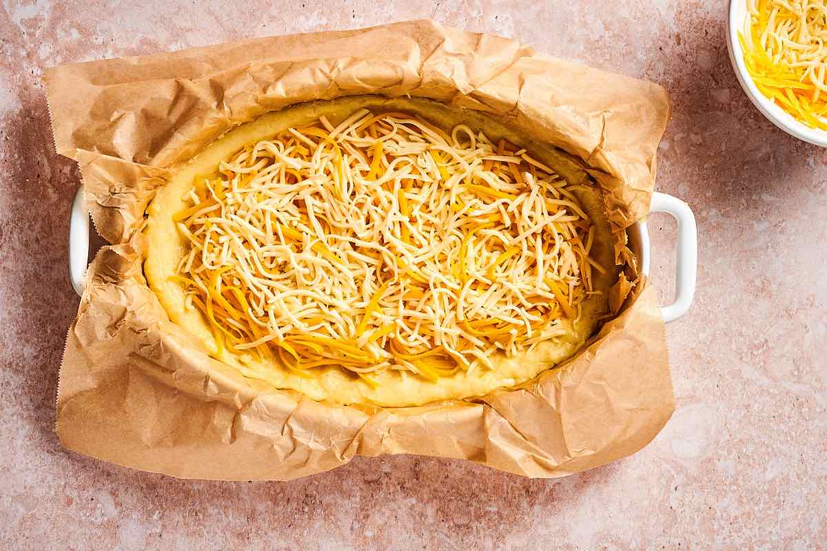 dough in baking dish with shredded cheese on top.