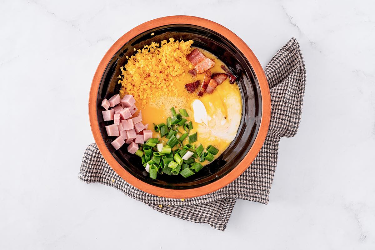 eggs, bacon, ham, shredded cheese and green onion in mixing bowl.