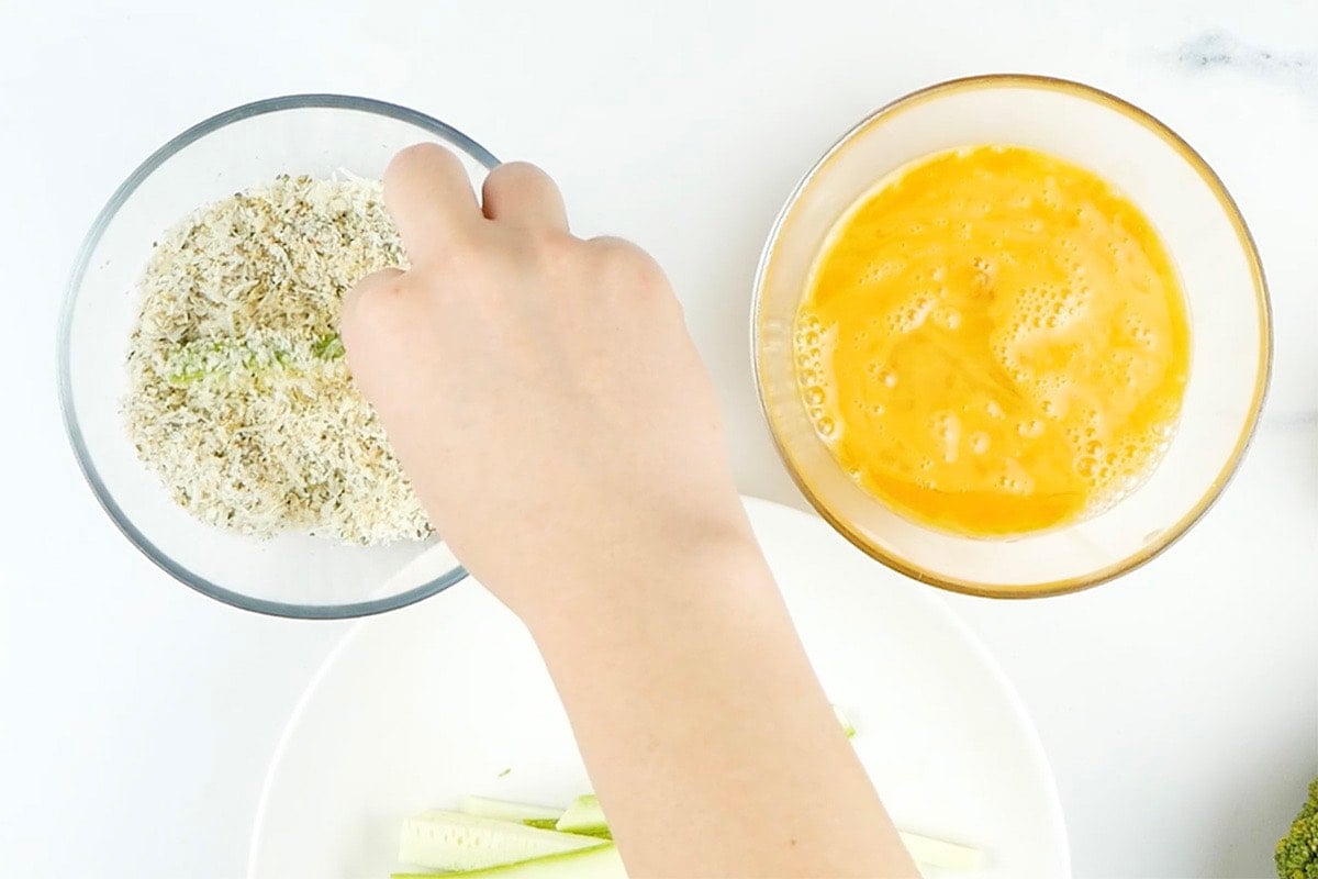 dipping raw zucchini fries in breading and egg.