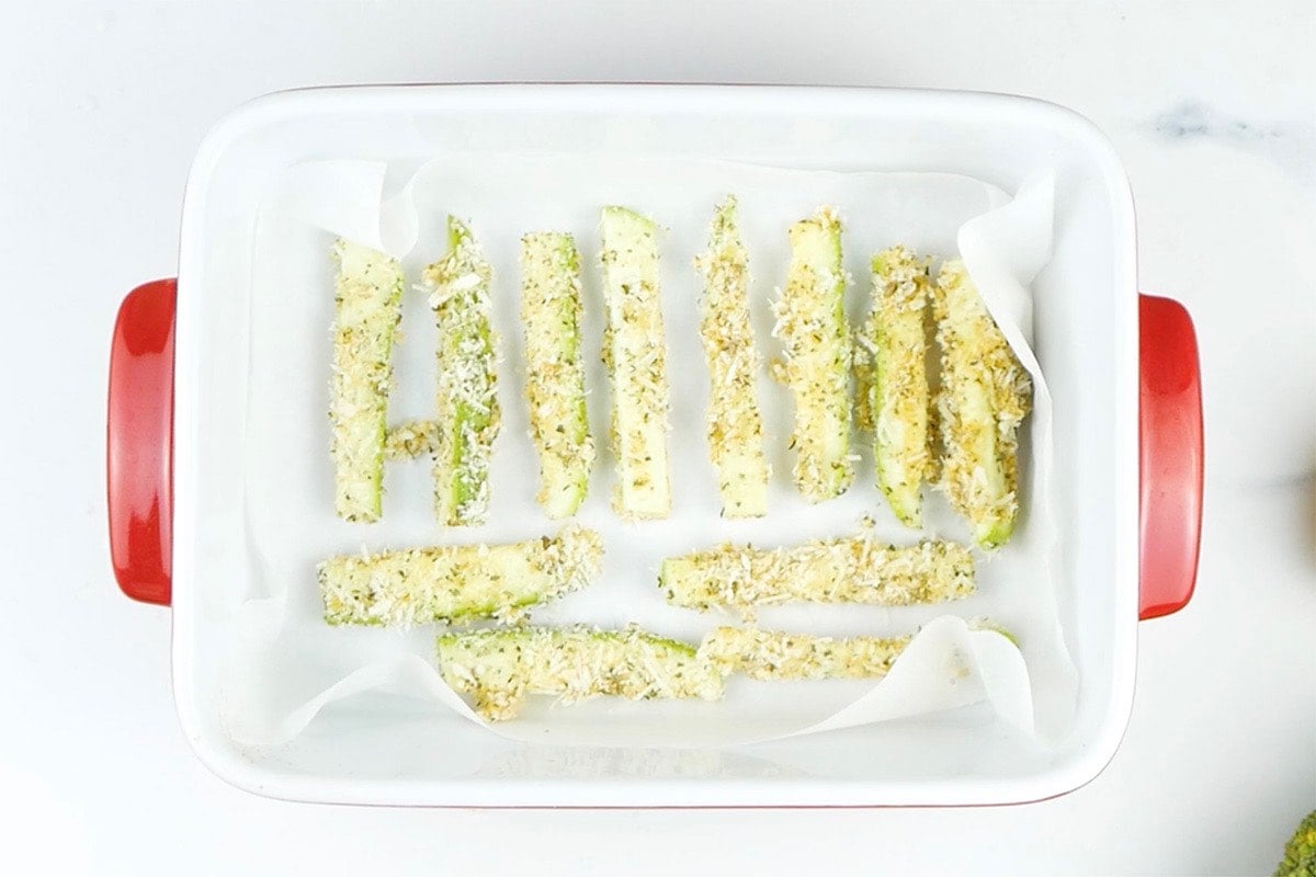 breaded zucchini fries in a baking dish.