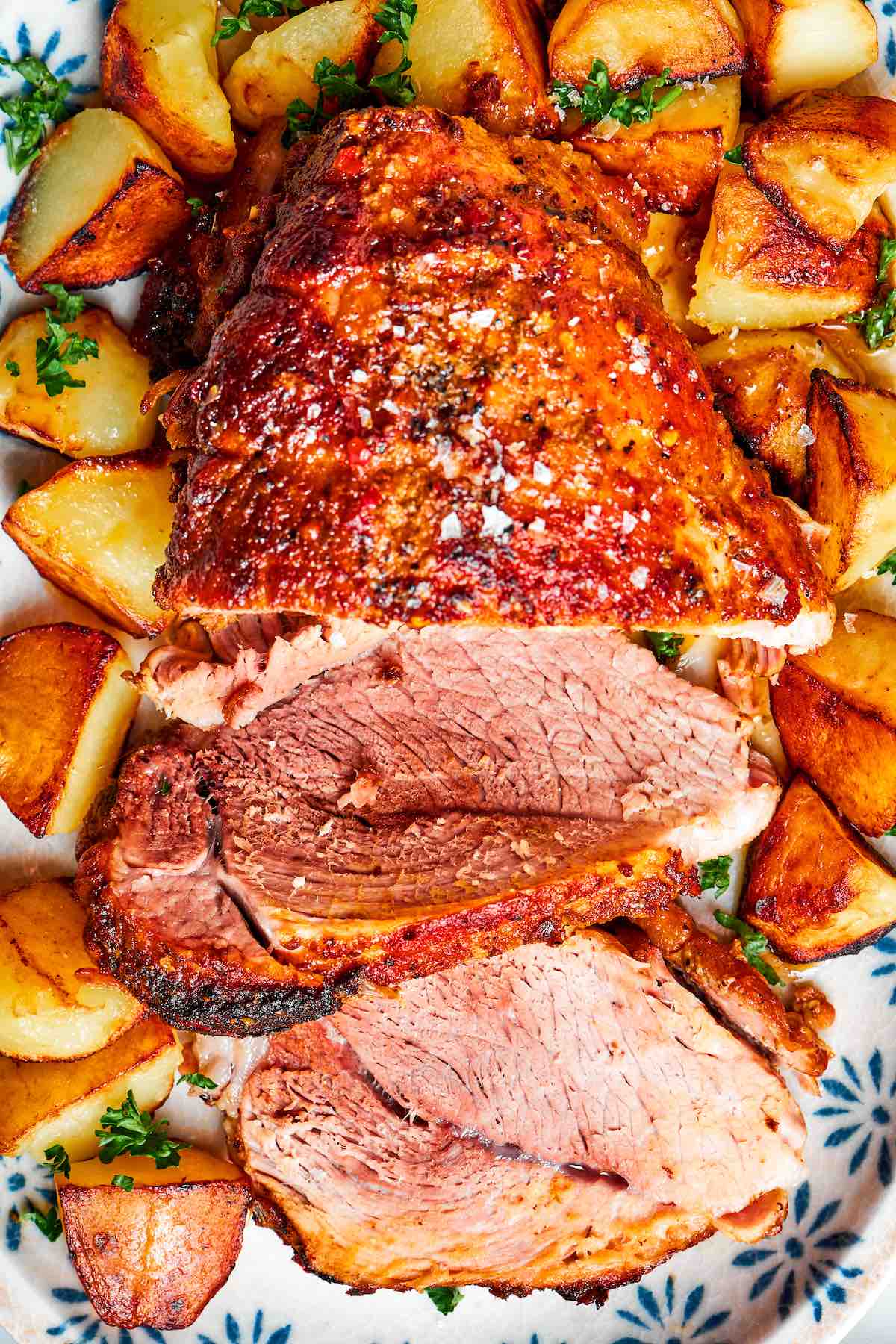 sliced pork shoulder roast with seasoned potatoes.