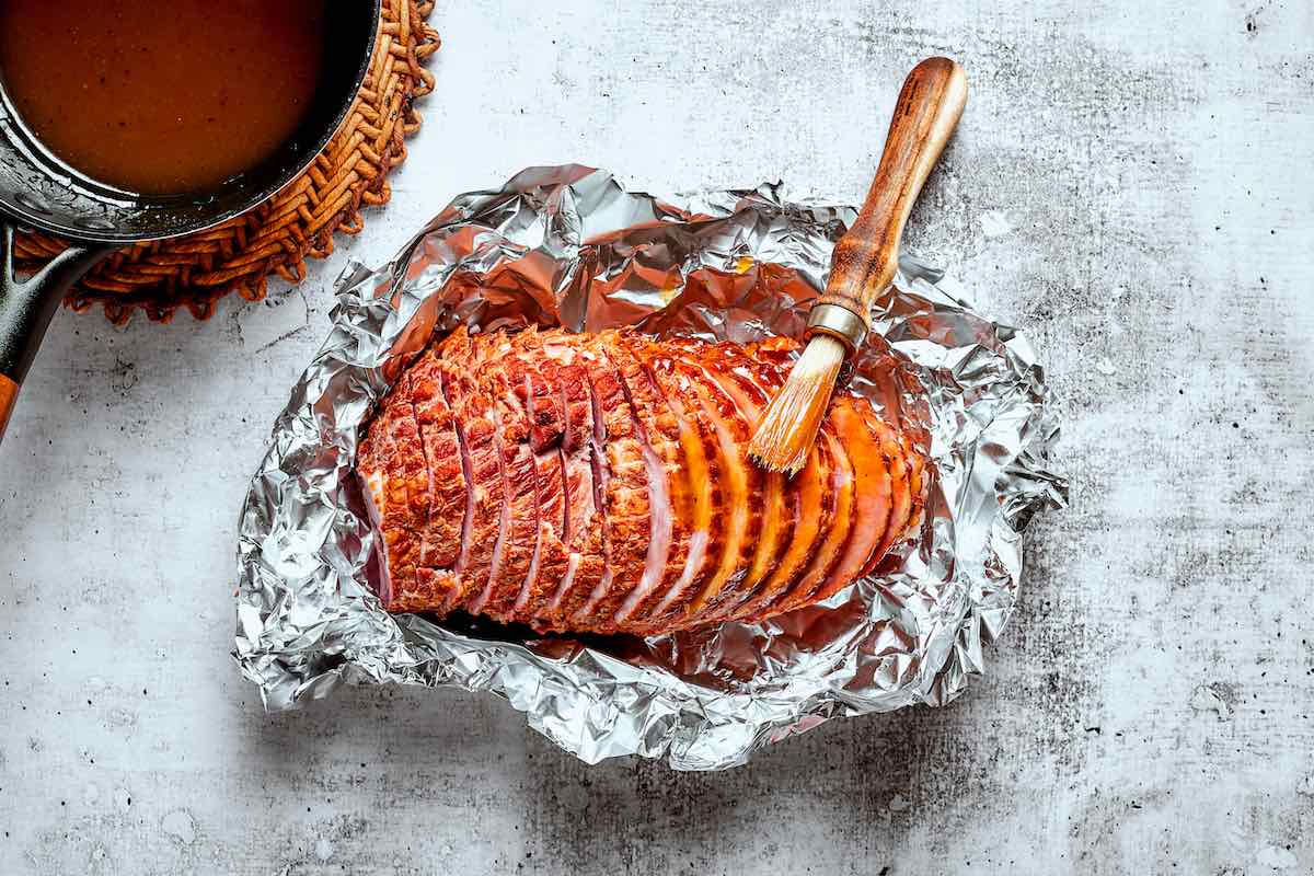 brushing the glaze over the sliced ham.