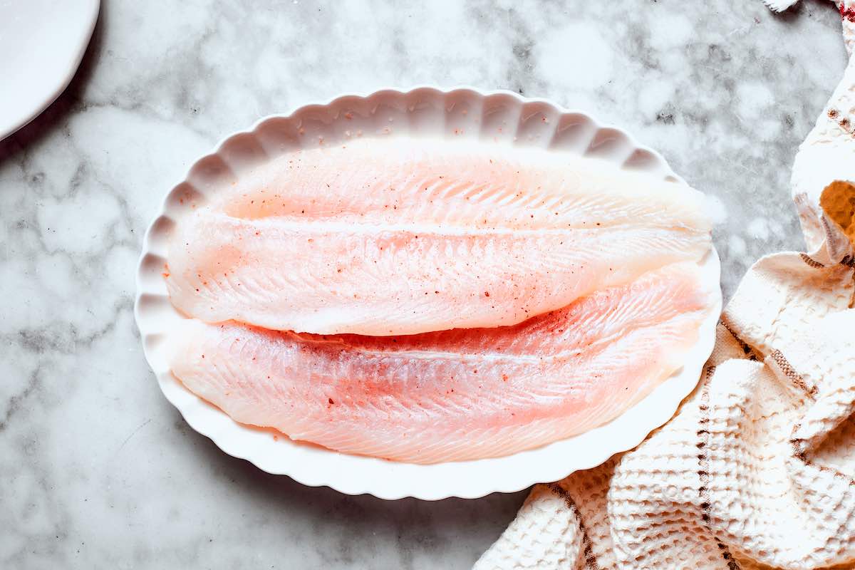 raw pollock fillets on a white plate.