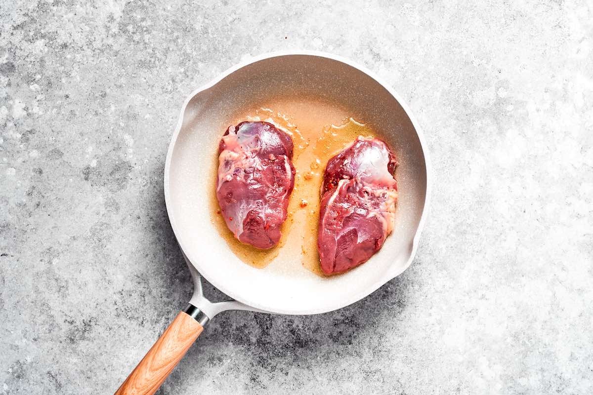 searing duck breasts in a skillet with oil.