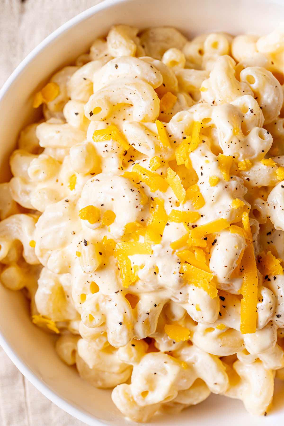 high protein mac and cheese in a bowl with extra shredded cheese on top.