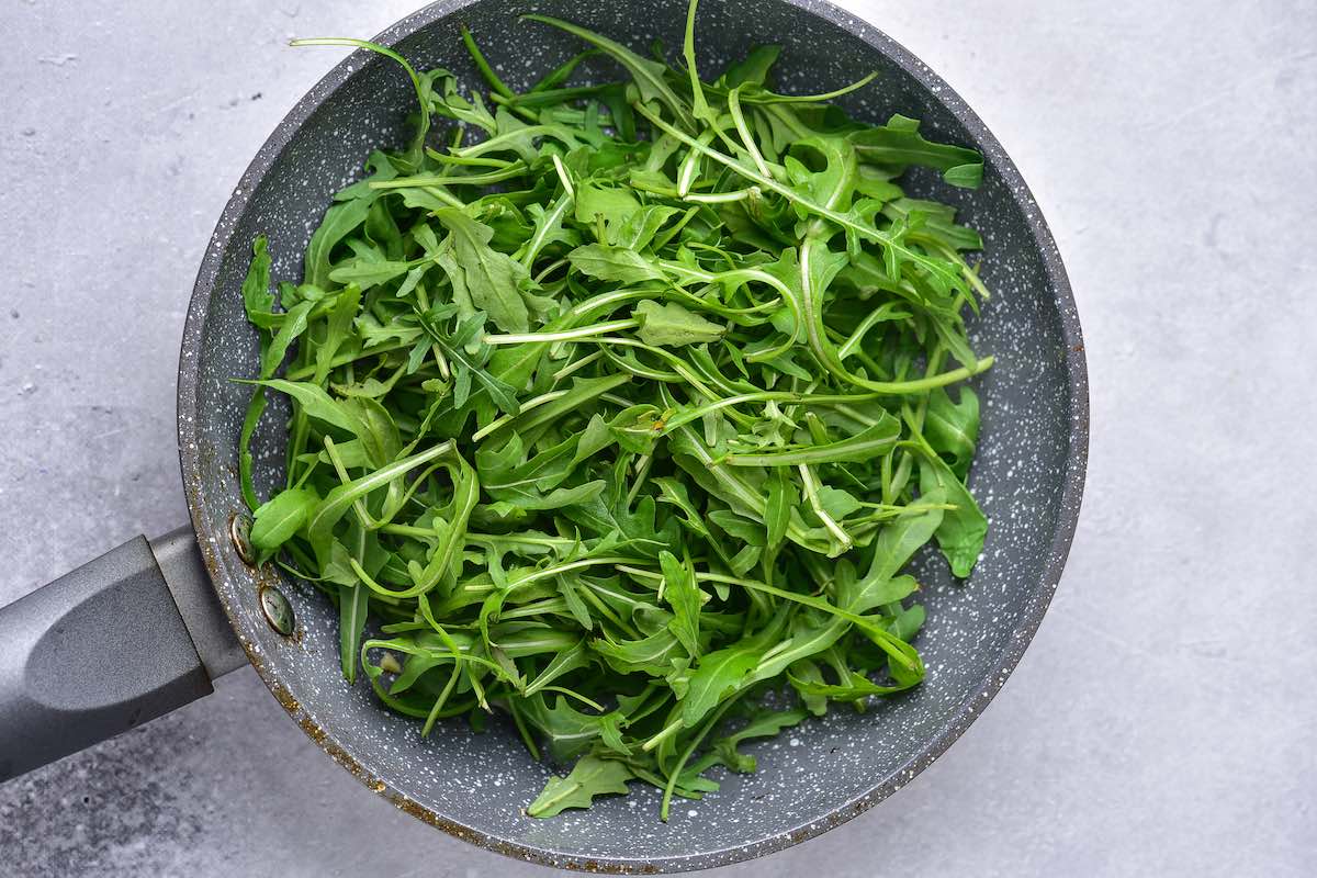 raw arugula in a pan.