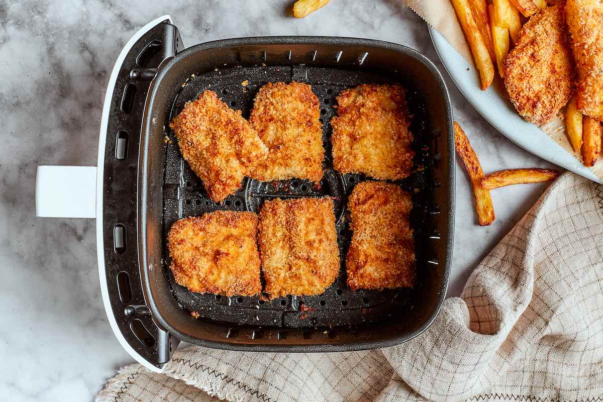 crispy breaded fish in air fryer basket.