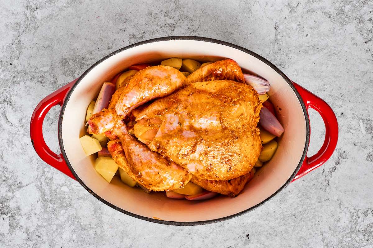 raw seasoned chicken in a Dutch oven over vegetables.