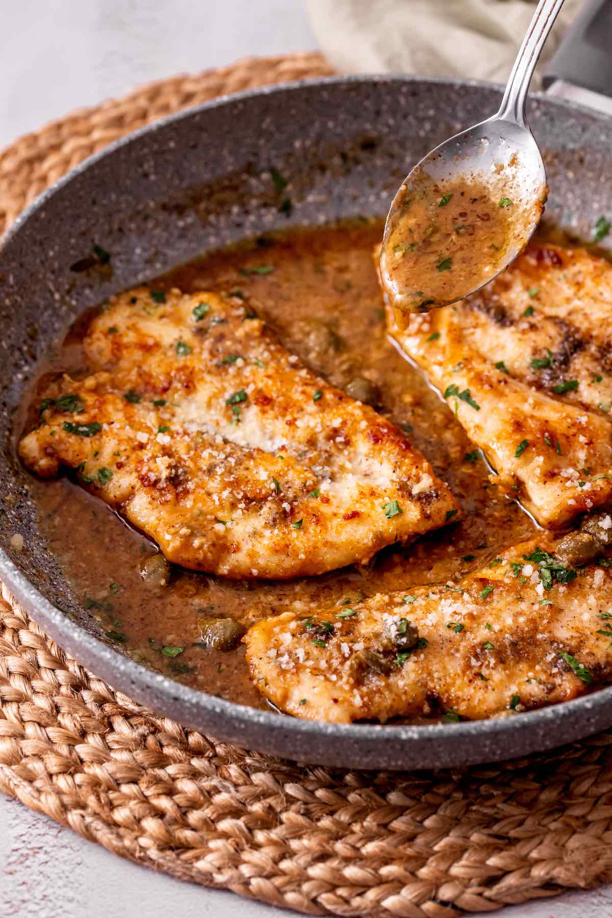 chicken piccata in a skillet with piccata sauce.