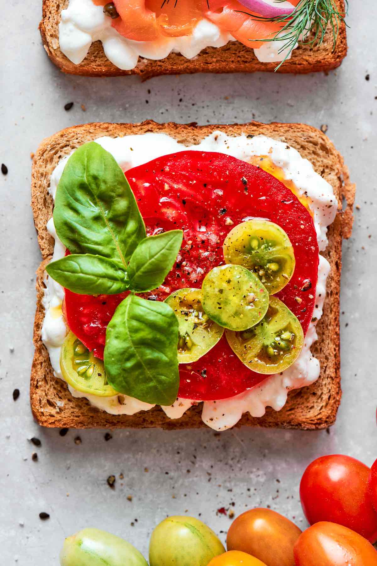 cottage cheese toast with sliced heirloom tomato, grape tomatoes, basil, and flaky salt and pepper.
