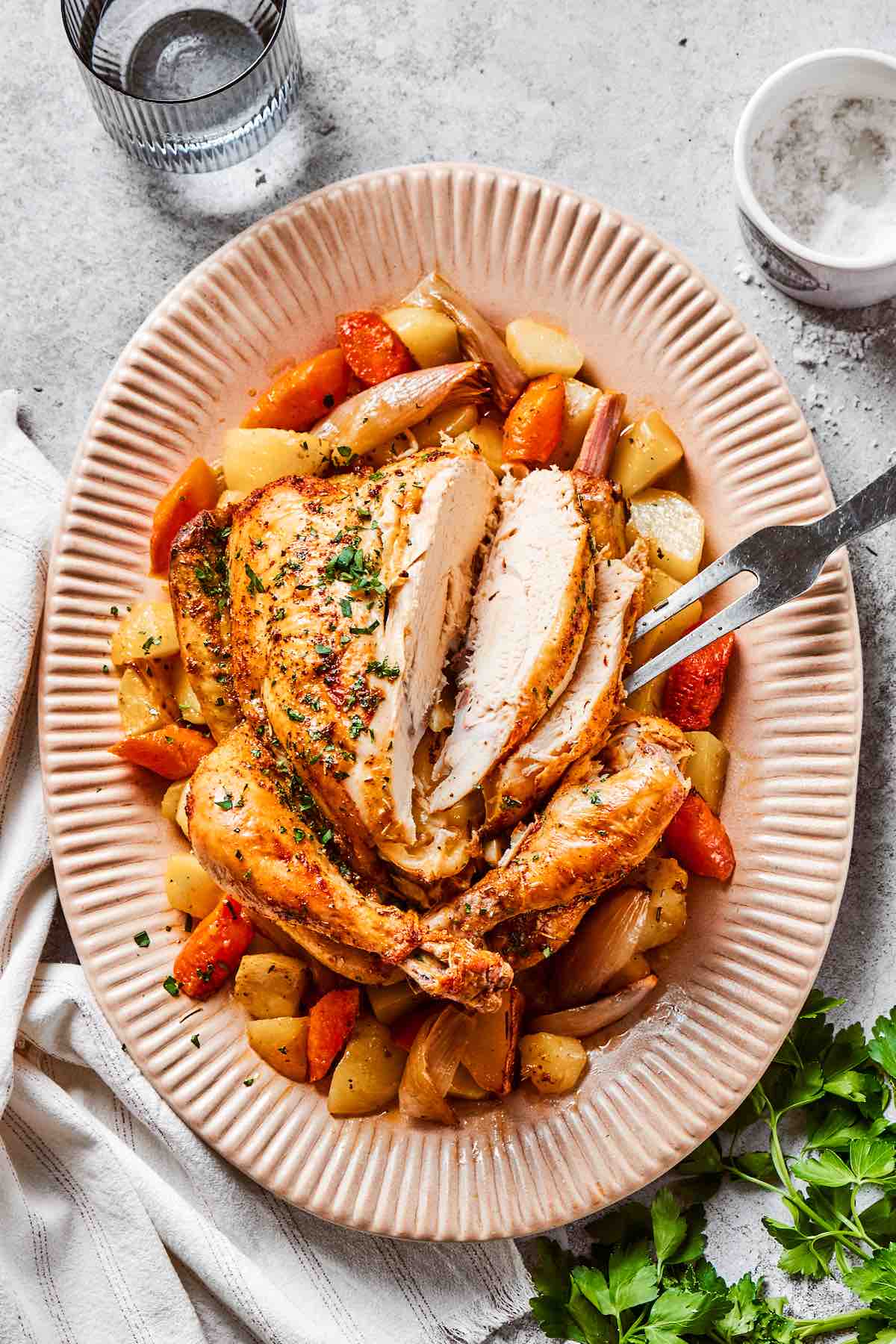 Carved Dutch oven roast chicken on a plate with vegetables.