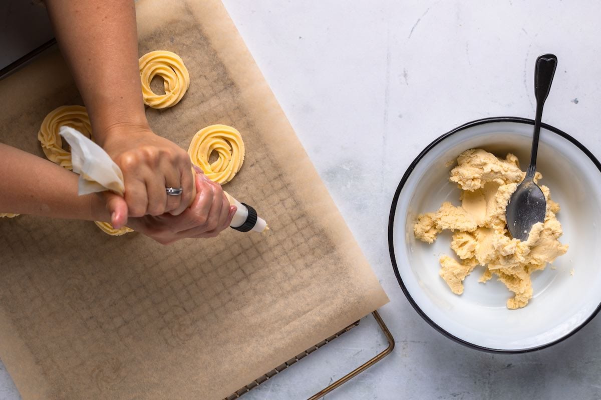 piping butter cookie dough on parchment paper.