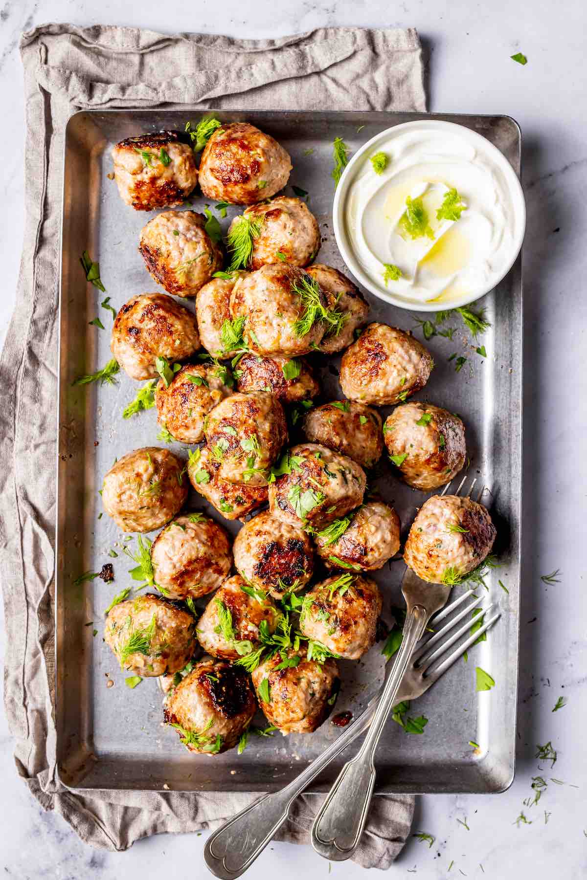 juicy pork meatballs on a serving dish with garlic yogurt sauce.