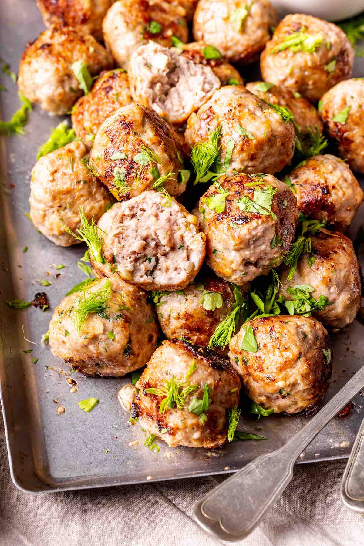 pan-fried pork meatballs with fresh herbs on top.
