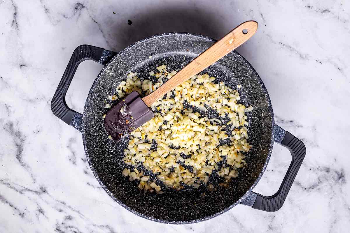 onion, garlic, and fennel sauteing in a skillet.