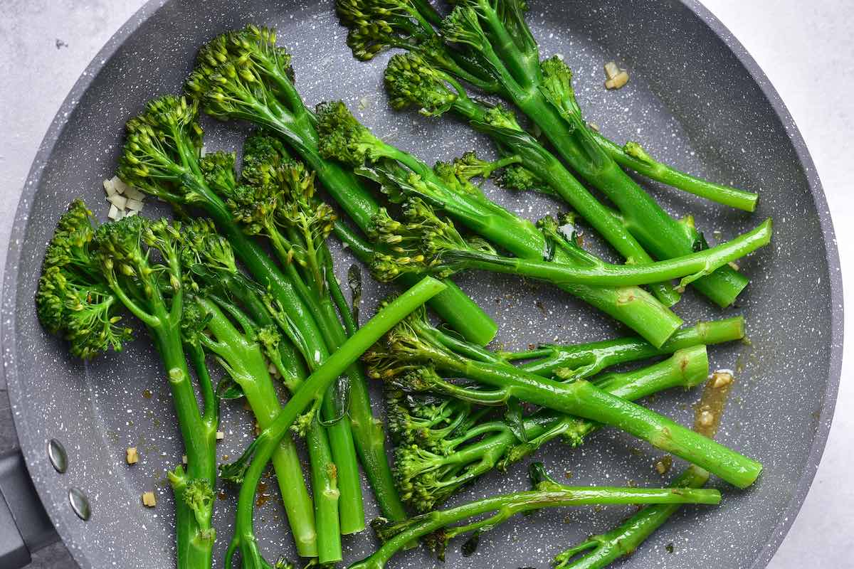 sauteing broccolini in a skillet with butter and oil.