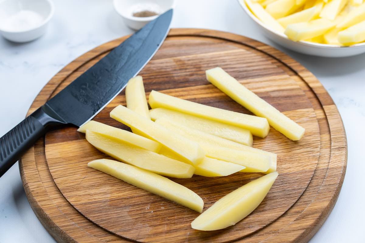 slicing raw jicama on a chopping board.