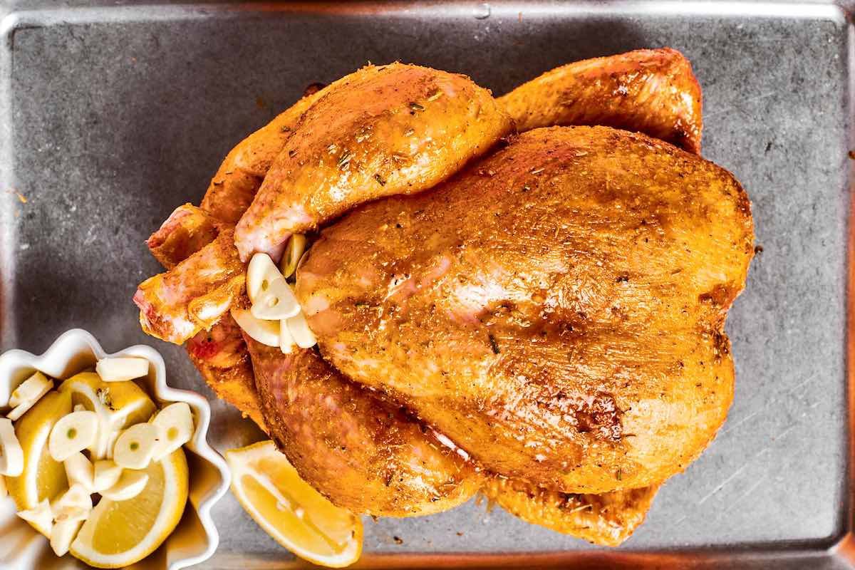 stuffing seasoned raw chicken with garlic and lemon slices.