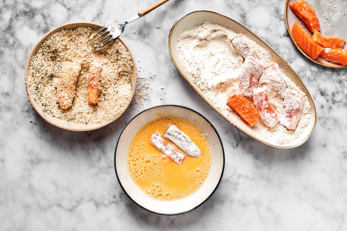 dredging salmon sticks in flour, bread crumbs, and egg.