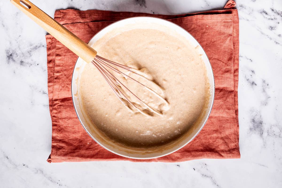 oat milk pancake batter in a bowl with a whisk.